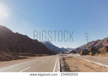 A Two-lane Highway To Each Side In The Midst Of A Hot Desert With Many Traffic Signs On The Move In