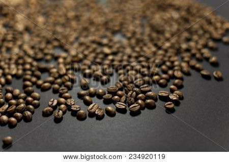 Spilled Roasted Coffee Beans On A Black Background.