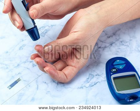 Diabetes Checking Blood Sugar Level. Woman Using Lancelet And Glucometer At Home.
