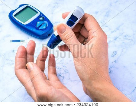 Diabetes Checking Blood Sugar Level. Woman Using Lancelet And Glucometer At Home.