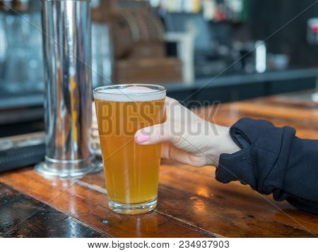 Woman Reaching For Full Pint Glass Of Ipa In A Bar In A Brewery