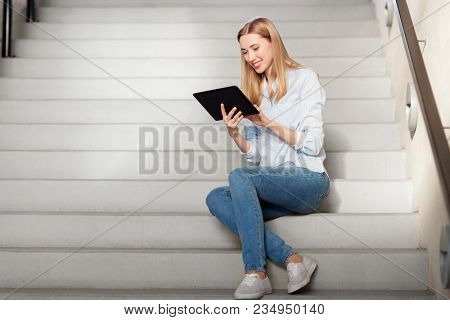 technology, business and corporate concept - happy woman or student with tablet pc computer sitting on stairs