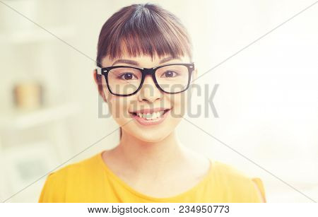 people, education, vision and portrait concept - happy asian young woman or teenage student girl in glasses at home