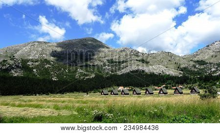 View Of The Mountains, The Meadow, The Beautiful Sky And Small Houses. High In The Mountains. Backgr