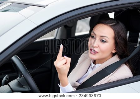 Pretty woman driver is showing middle finger to someone, boorishness on the roads.