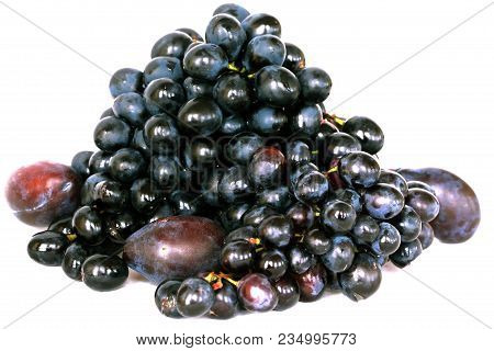 A Bunch Of Black Grapes And Blue Plums On A White Background.