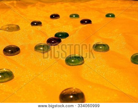 Glass Pebbles Lie On A Flowing Shining Golden Fabric