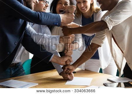 Overjoyed Younger Older Mixed Race Teammates Making Pyramid Of Fists.