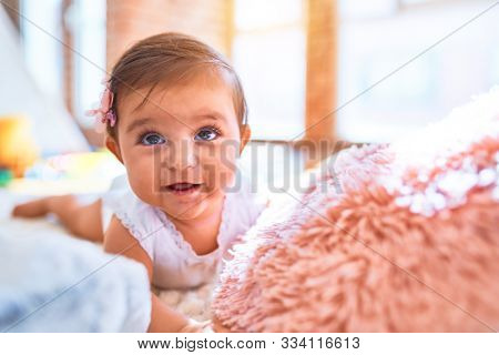 Beautiful infant happy at daycare around colorful toys lying on blacket