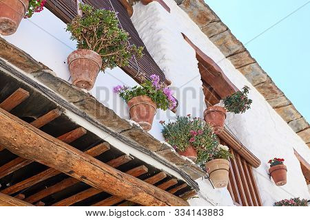 Clay Pots With Flowers Weigh On The Wall Of A White House With A Tiled Roof In The Old Town Of Capil