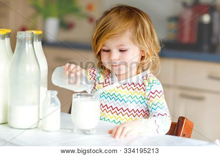 Adorable Toddler Girl Drinking Cow Milk For Breakfast. Cute Baby Daughter With Lots Of Bottles. Heal