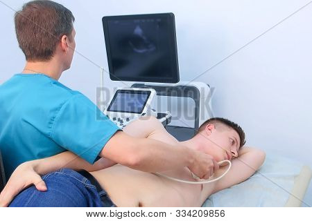 Echocardiography. Man Doctor Examining Guy Patients Heart By Using Ultrasound Equipment. He Runs Ult