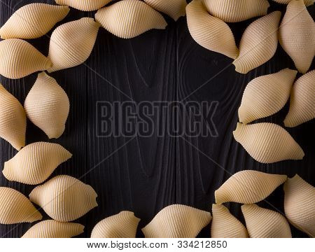 Top View Of Conchiglie Pasta On Black Wooden Table With Space For Your Text