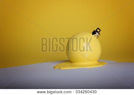 New Years Christmas Ball Painted In Yellow Lay In A Puddle Of Paint On A White Sheet Of Paper. Yello