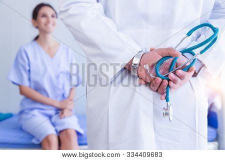 Doctor Hold Stethoscope Behind Back In Patient Room At Hospital Or Clinic With Smiley Patient Face B