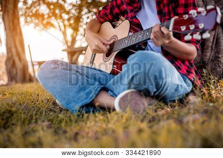 Woman Is Playing Acoustic Guitar In Park.