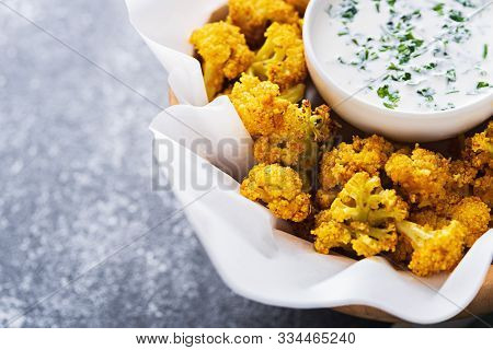 Close Up Baked Cauliflower With Sour Cream Sauce And Greens On Gray Background
