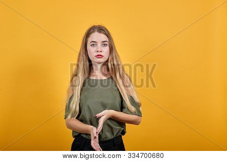 Confused Young Woman In Haki Shirt Putting Hand Keeping Hand Down, Looking Serious Isolated On Orang