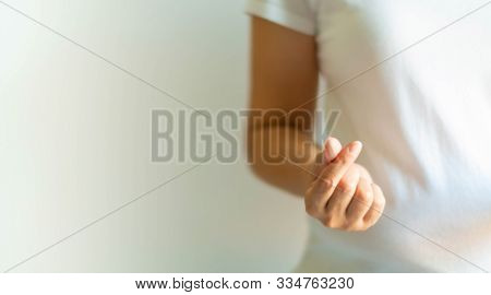 A Woman In A White T-shirt Making Hand Signs To Be Heart Shape From The Tip Of Thumb And Index Finge