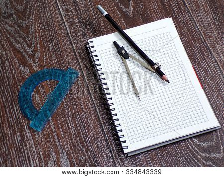 Compasses With Pencil And Ruler In The Workplace With A Notebook For Drawings.