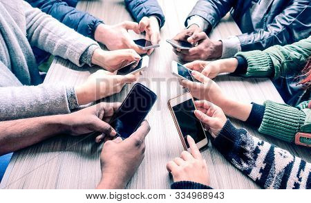 Group Of Friends Using Phone Around Meeting Table - Multiracial People Hands Holding Smartphone Sitt