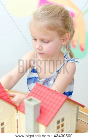 Liten flicka leker med dockskåp