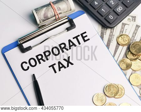 Phrase Corporate Tax Written On Paper Clipboard With Calculator,a Pen,coins And Fake Money. Business