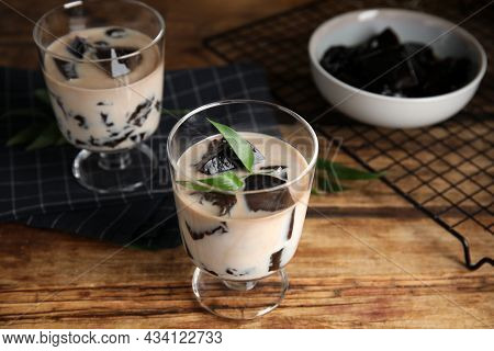Glass Of Milk With Grass Jelly And Green Leaf On Wooden Table