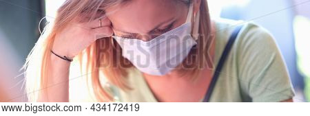 Anxious Sad Woman In Medical Protective Mask Sits At Table