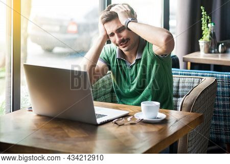 Mistake. Young Sad Businessman In Green T-shirt Sitting And Working On Laptop And Holding His Head B