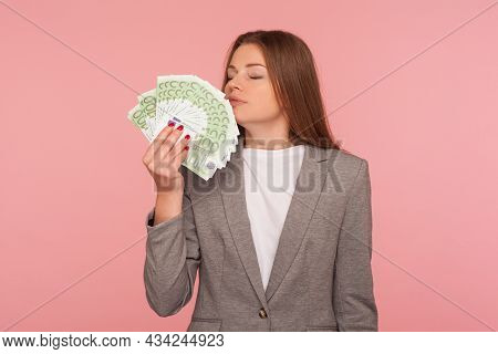 Greedy For Money. Avaricious Businesswoman In Suit Jacket Smelling Euro Banknotes With Expression Of