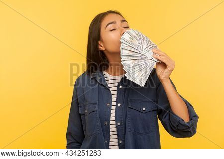 Greedy For Money. Portrait Of Avaricious Rich Girl In Denim Shirt Smelling Earned Dollar Banknotes, 