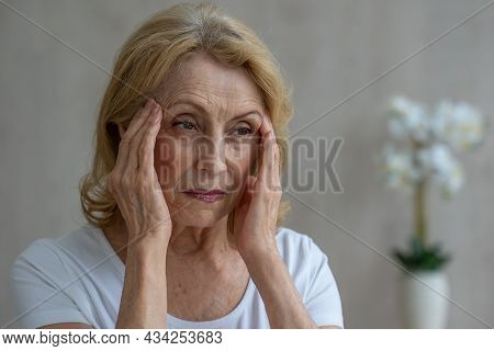 An Elderly Woman Has Headaches, She Touches Her Head With Her Hands, Reports Symptoms Of Dizziness, 