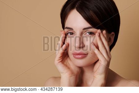 Close-up Of Gorgeous Young European Woman Touching Her Face With Hands Doing Face Fitness Exercises.
