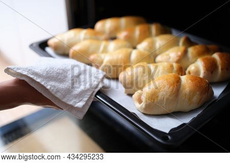 Housewife Taking Hot Delicious Mouth Watering Buns Out Of Oven On Baking Sheet Closeup
