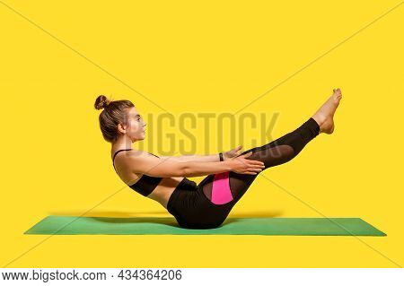 Fitness Girl With Hair Bun In Tight Sportswear Doing Sport, Physical Training On Gym Mat, Reaching H
