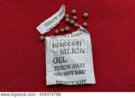 Desiccant Silica Gel On Red Background. Synthetic Substance Absorbing Moisture
