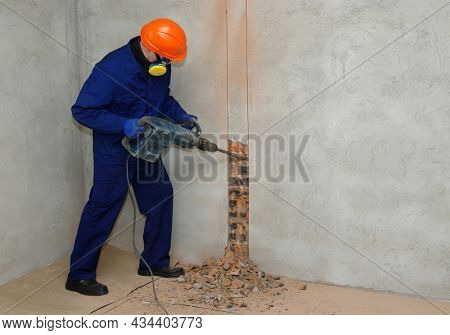 Worker with jackhammer breaking brick wall 