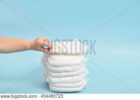 A Stack Of Disposable Panties On A Blue Background With Children's Hands. Small Children's Hands Gra