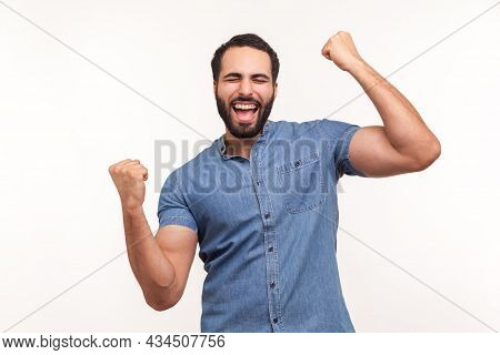 Euphoric Thrilled Man With Beard Screaming Hurray Raising Hands Up, Celebrating His Triumph And Vict