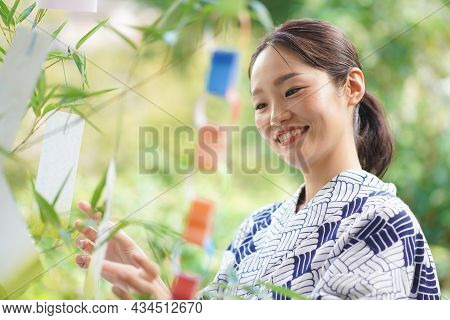 A Woman Wearing A Strip Of Paper On Tanabata Bamboo