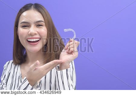 Young Smiling Woman Holding Invisalign Braces In Studio, Dental Healthcare And Orthodontic Concept..