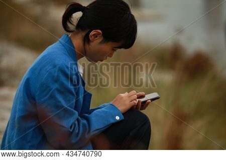 A Woman Who Is Depressed Looking At A Smartphone