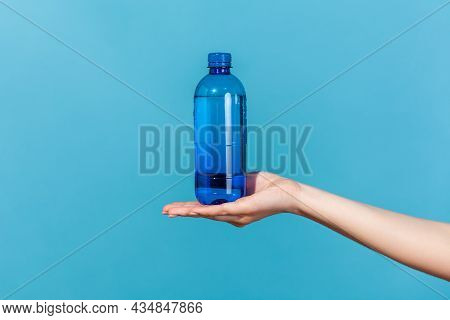 Close Up Female Hand Demonstrating Plastic Blue Bottle With Mineral Water, Advertising Of Fresh Pure