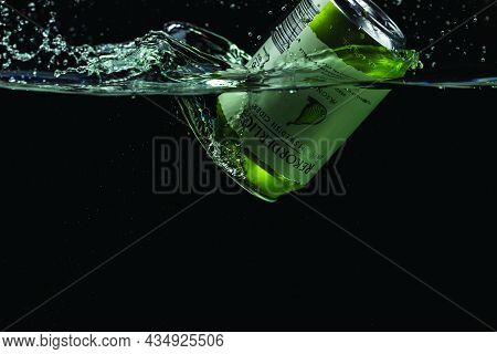 Close Up View Of Can Of Pear Sider Falling Into Water Isolation On Black Background. Sweden. Uppsala