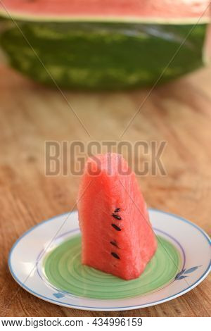 Watermelon Slice In Foreground With On The Background Half Of The Fruit
