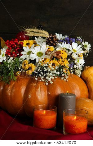 Beautiful autumn composition in pumpkin with candles on table on wooden background