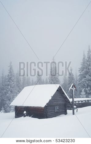 Cross with a crucifix and a wooden hut in the mountains. Winter landscape. Ukraine, the Carpathian Mountains, the ridge Kukul