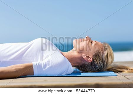 beautiful senior woman relaxing peacefuly on yoga mat