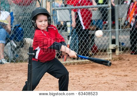 Young baseball player hitting ball off a tee during game